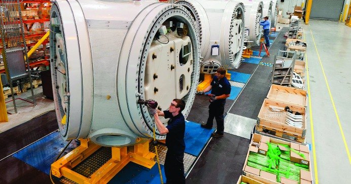 Technicians assembling large machine housings on an assembly line